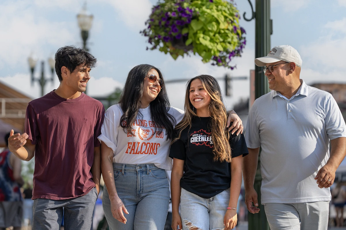 A family of four walking in downtown Bowling Green, Ohio smiling and talking.